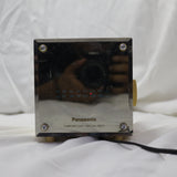 Vintage Panasonic cube clock radio with mirrored display and rotary dials, showing wear and tear.