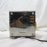 Vintage Panasonic cube clock radio with mirrored display and rotary dials, showing wear and tear.